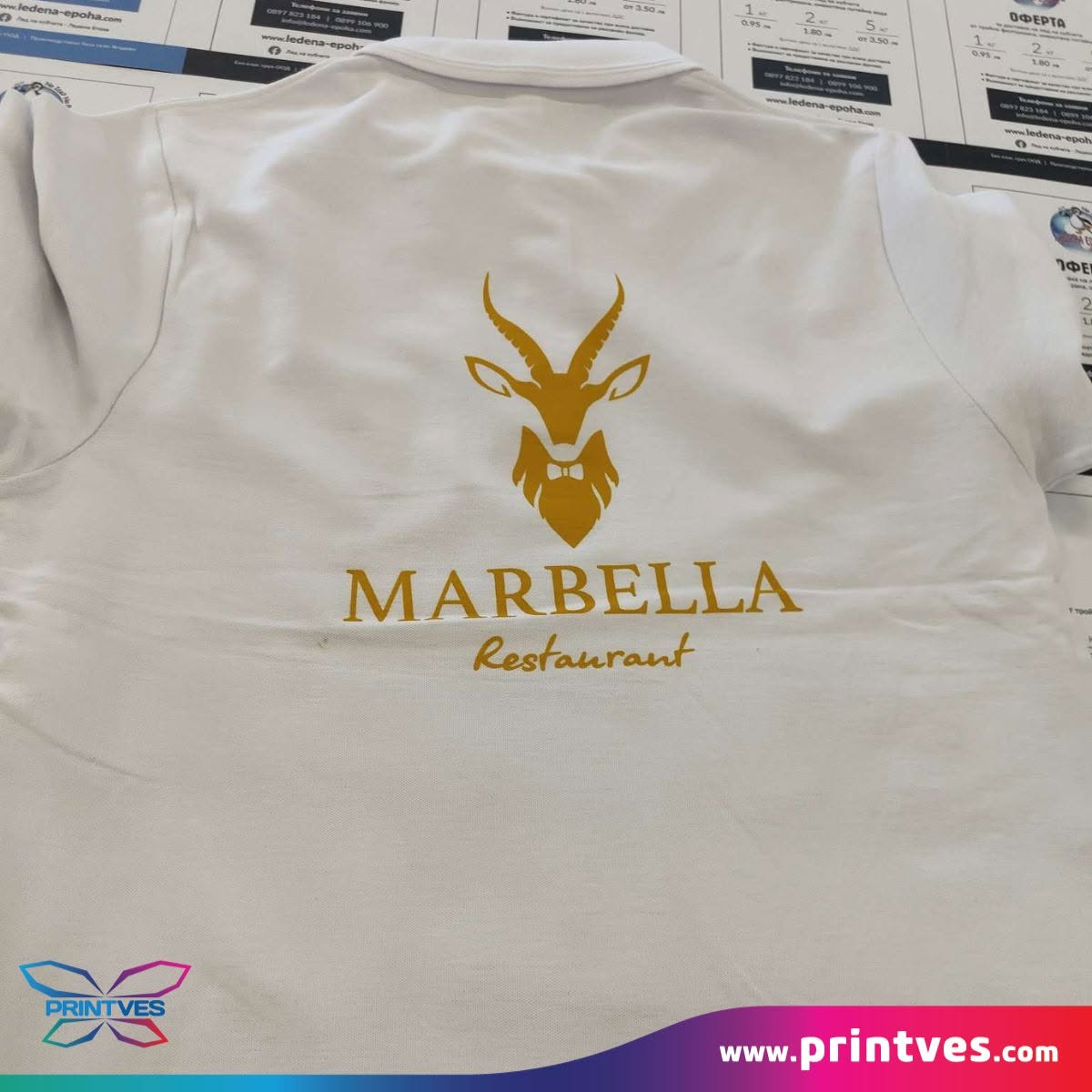 Бяла дреха със златно лого на ресторант Marbella