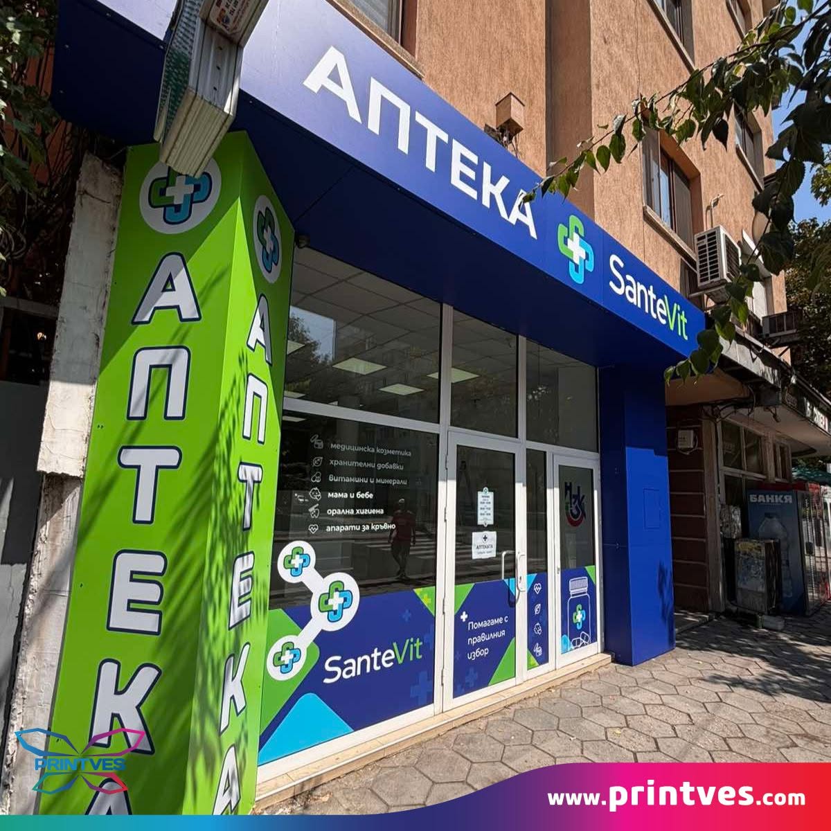 Фасада на аптека Santevit със зелени и сини светещи табели