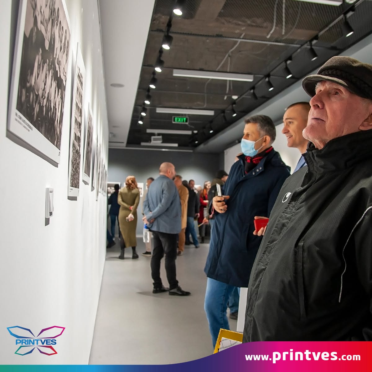 Посетители в галерия с отпечатани фотографии по белите стени