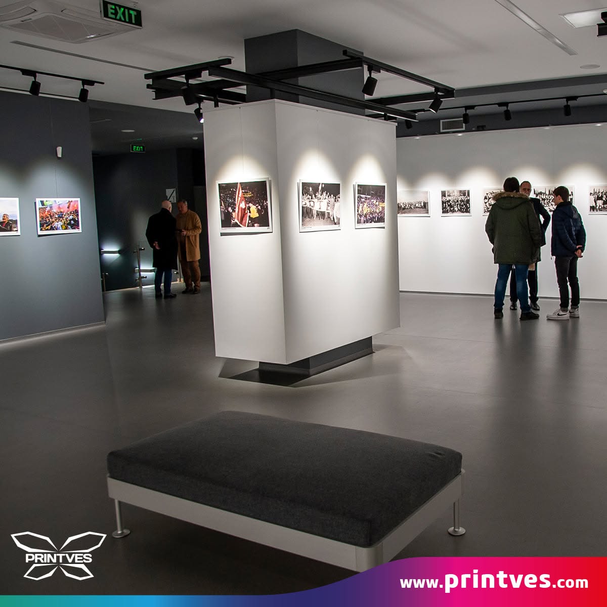Изложбена зала с отпечатани фотографии по стени и колони