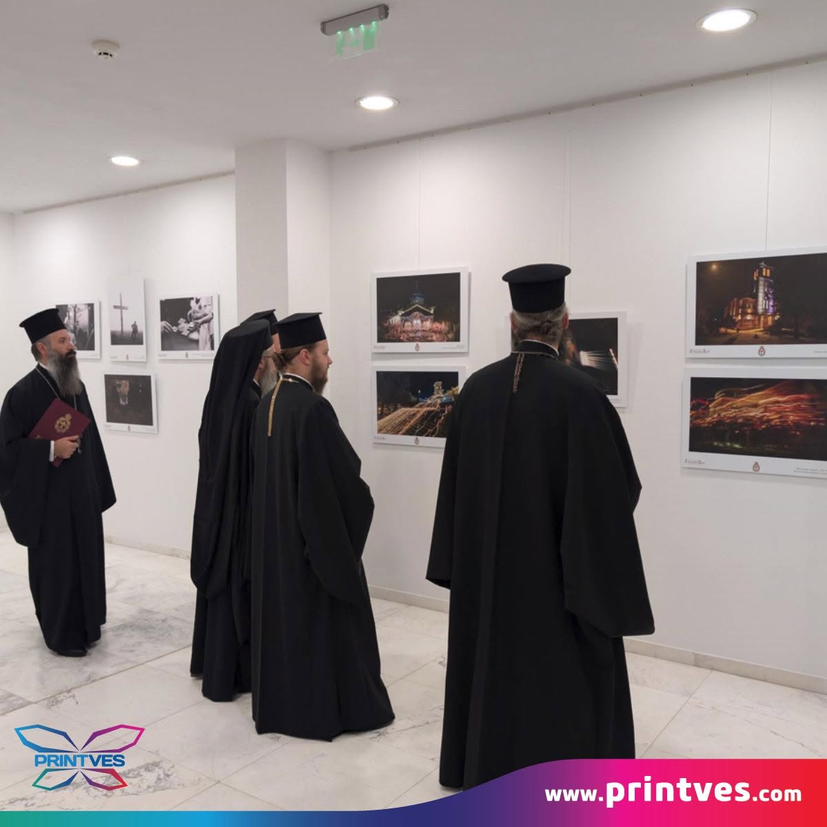 Духовници разглеждат фотоизложба с отпечатани кадри на стената